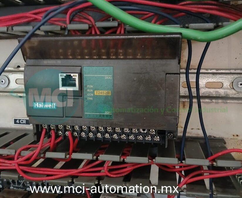 un PLC industrial mediante computadora portátil para verificar la CPU, módulos de entradas y salidas, comunicaciones y programa de control en un sistema de automatización industrial.