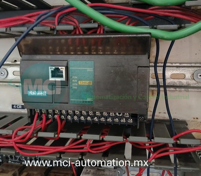 un PLC industrial mediante computadora portátil para verificar la CPU, módulos de entradas y salidas, comunicaciones y programa de control en un sistema de automatización industrial.
